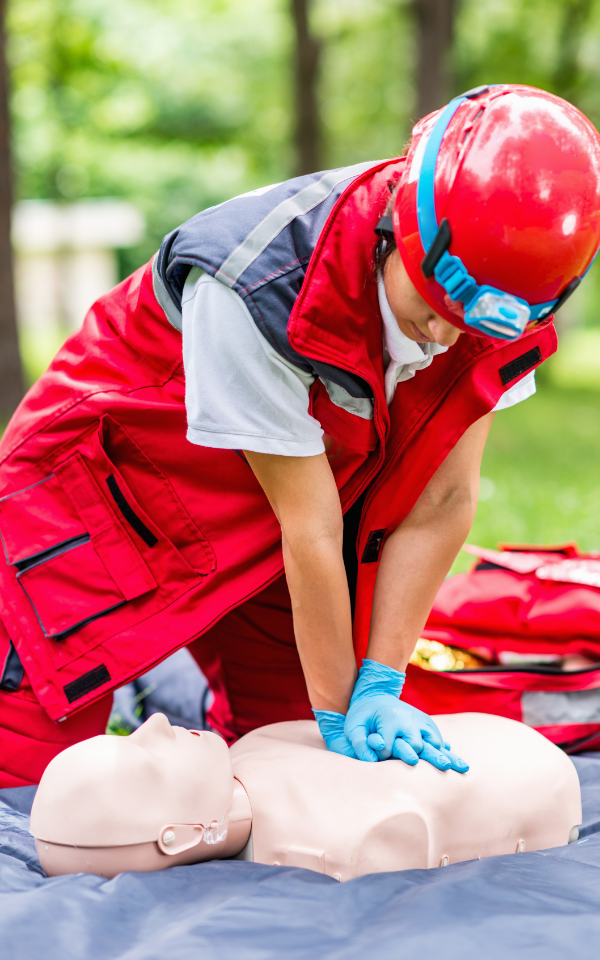 Rescuer in a red uniform practicing CPR on a training manikin