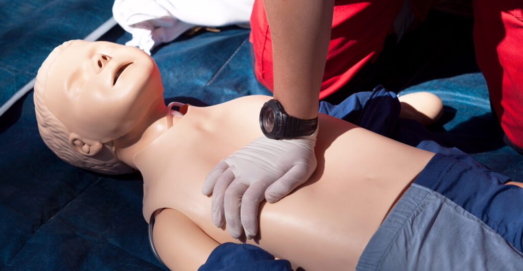 Hands performing chest compressions on a CPR training manikin